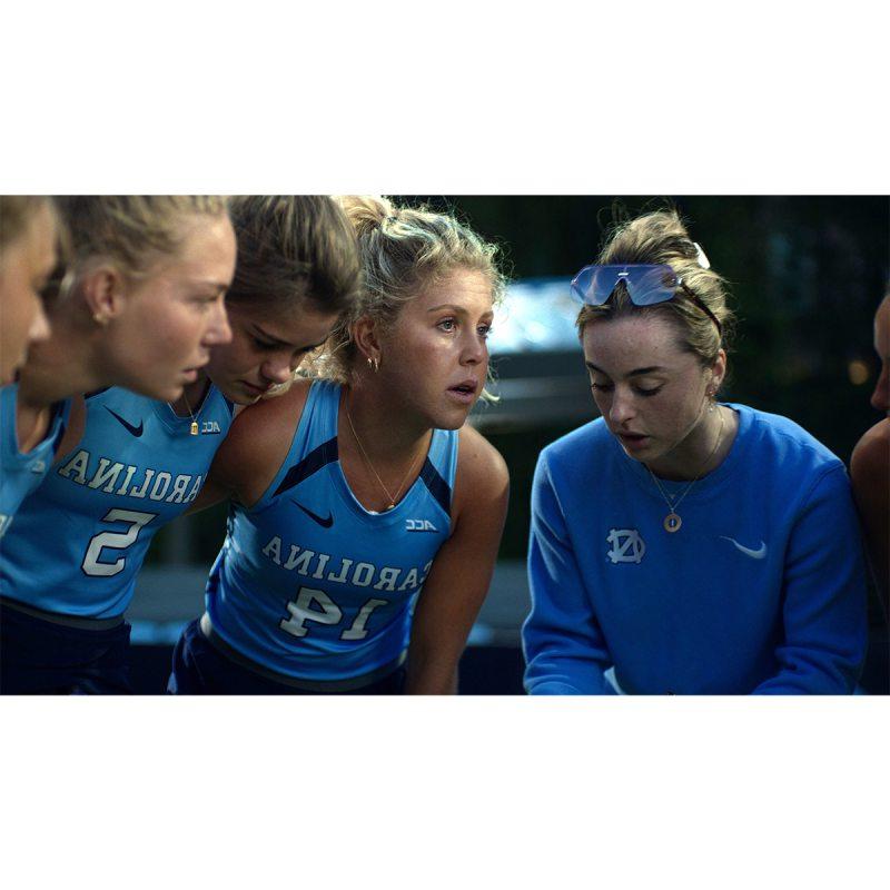 Katie Dixon in a huddle with her field hockey coach and teammates.